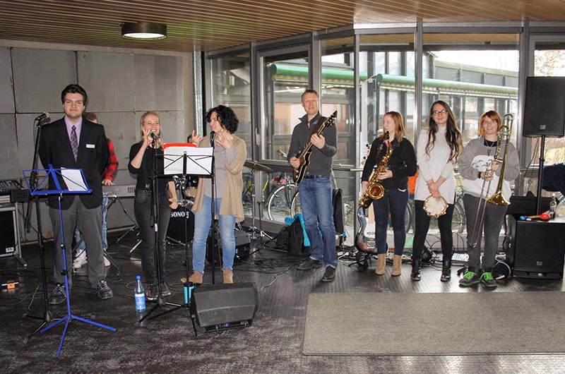 Gruppenbild der Schulband, 8 Personen mit Instrumenten oder Mikrophonen